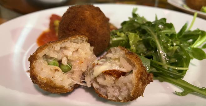 Arancini auf einem Teller mit etwas Salat